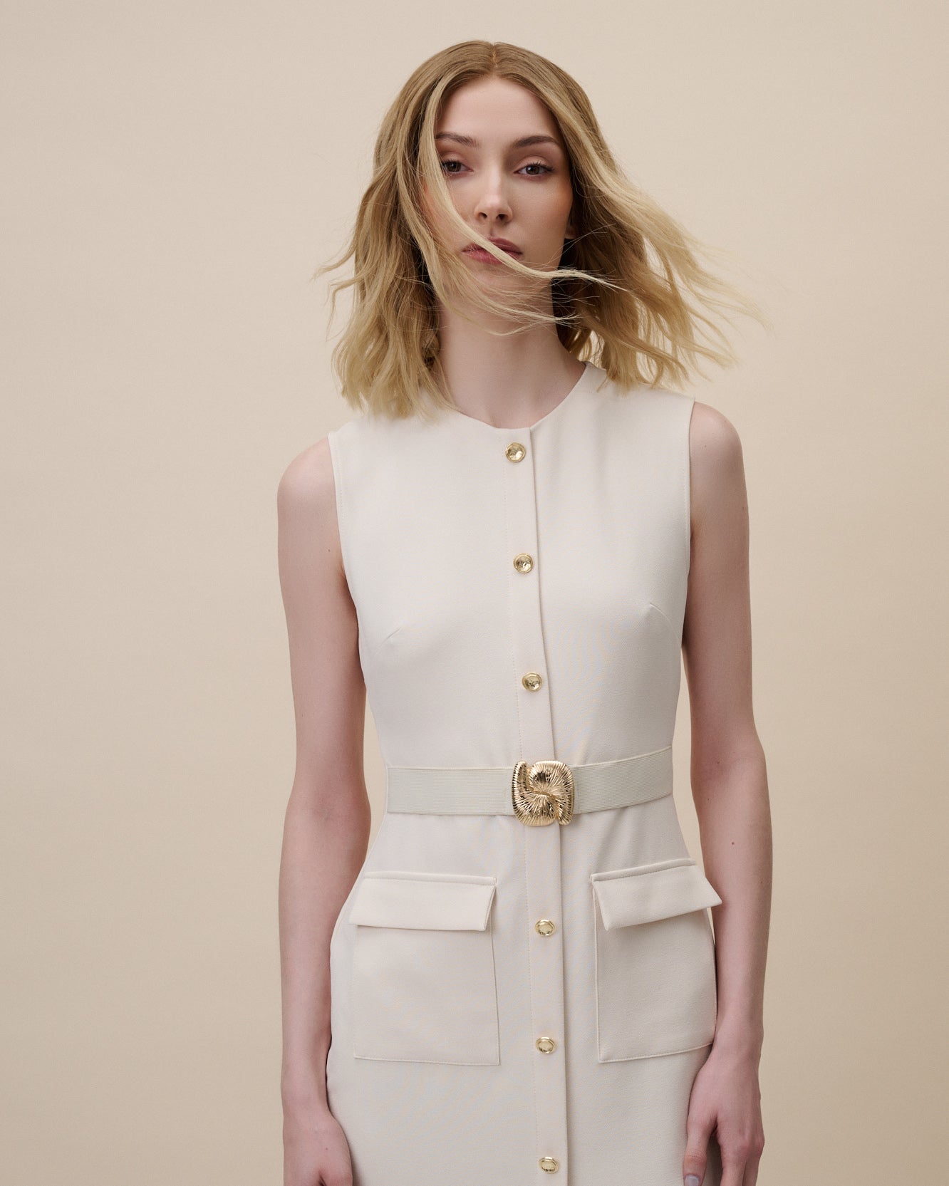 Statice Wig 30 cm medium blonde human hair wig with natural golden tones and darker root, neatly cut for a modern, elegant look, shown on model.