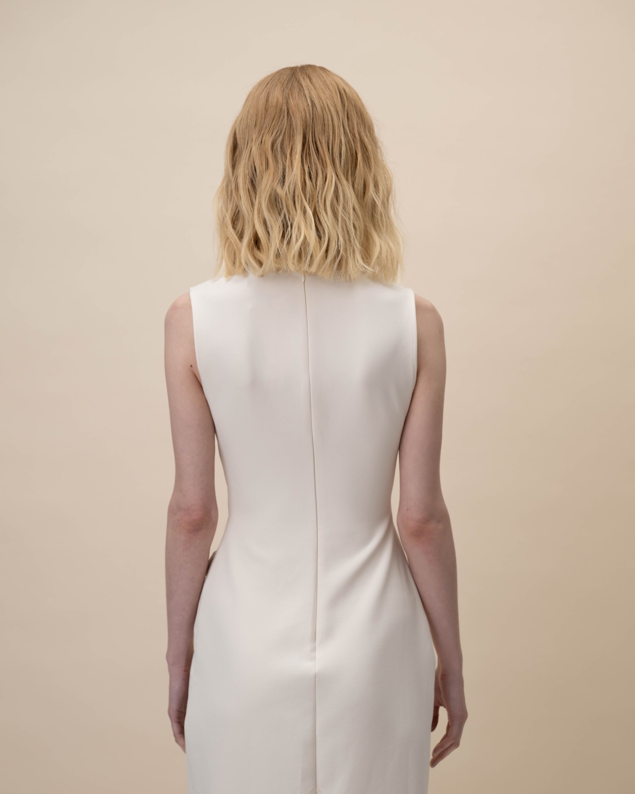 Statice Wig 30 cm Remy human hair wig in medium blonde with soft golden tones and natural darker root, shown from the back on model.