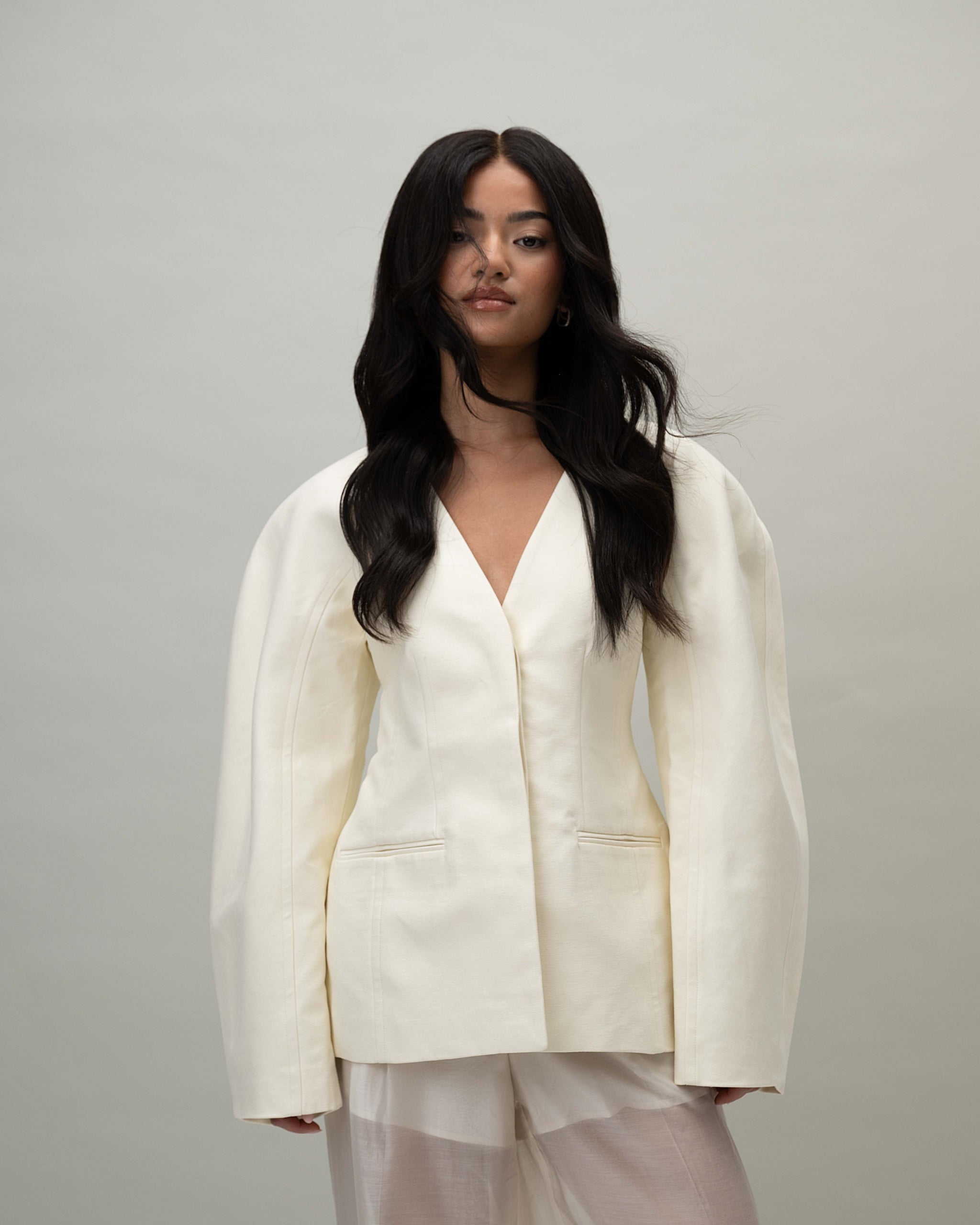 Model wearing wig. front view, white outfit. Aurora Wig – 40cm full lace wig in deep natural black; 100% Remy hair with pre-plucked hairline and HD lace; styled with soft layers.