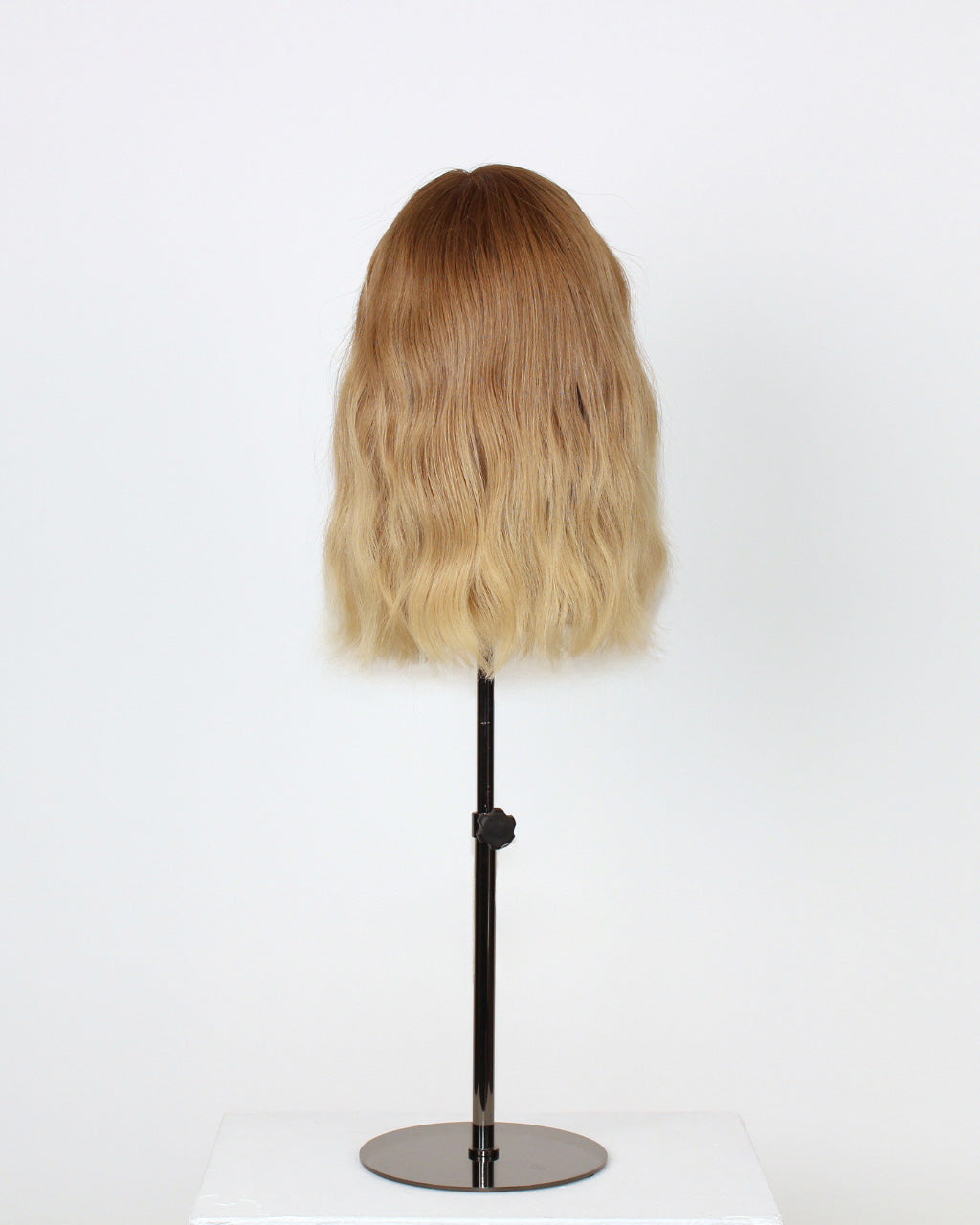Statice Wig 30 cm medium blonde Remy human hair wig with darker roots and softly layered finish, displayed on stand.